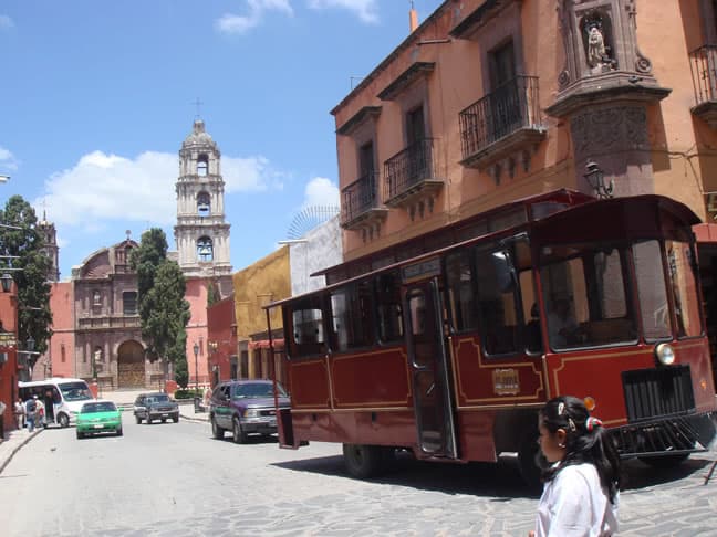The colonial tourist bus passing El Oratorio church during a daily San Miguel city tour